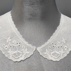 May include: White cotton lace collar with delicate floral embroidery. The collar has a scalloped edge and is perfect for adding a vintage touch to any outfit.