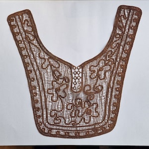 Può includere: Un colletto in pizzo marrone con un delicato motivo floreale. Il colletto è realizzato in pizzo fine e intricato e ha un bordo smerlato.