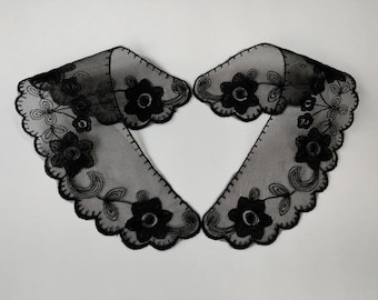 May include: A black lace collar with a scalloped edge and floral embroidery. The collar is made of sheer fabric and has a delicate, feminine look.