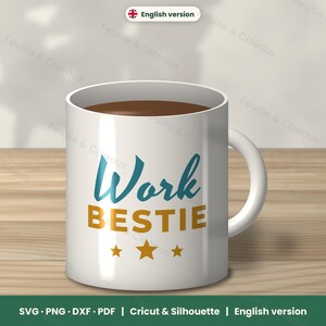Peut inclure: Un mug en céramique blanche avec le texte Work en écriture cursive bleu sarcelle et BESTIE en lettres capitales dorées, accompagné de trois étoiles dorées. Le mug contient un liquide brun foncé et possède une anse incurvée.