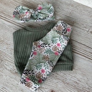 May include: A green waffle knit top and leggings set with a matching green and white floral headband. The leggings feature a white background with green leaves and pink flowers.