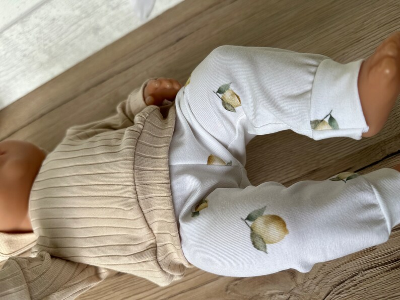 Puede incluir: Un beb&eacute; con una camisa de manga larga de color beige con textura de canal&eacute; y pantalones blancos con estampado de limones.