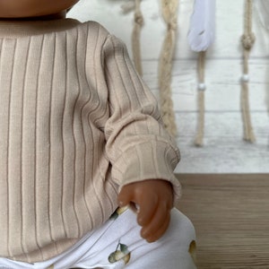 Puede incluir: Una camisa de manga larga de color beige con textura de canal&eacute; y cuello redondo.