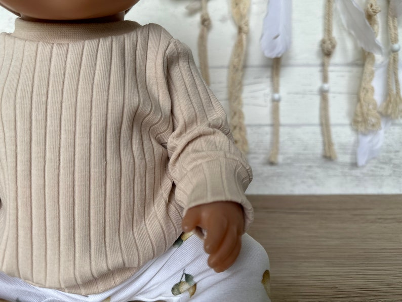 Puede incluir: Una camisa de manga larga de color beige con textura de canal&eacute; y cuello redondo.