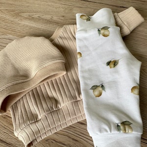 Puede incluir: Un su&eacute;ter beige de canal&eacute; y un gorro a juego con un pantal&oacute;n blanco con estampado de limones.