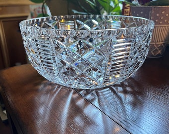 May include: A clear glass bowl with a cut crystal design. The bowl is sitting on a wooden table.