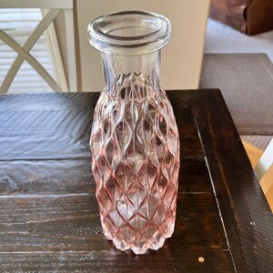May include: A clear glass vase with a textured, diamond-shaped pattern. The vase is pink and has a wide mouth.
