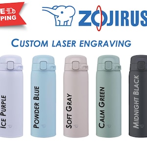 May include: Five insulated water bottles in various colors: Ice Purple, Powder Blue, Soft Gray, Calm Green, and Midnight Black. Each bottle has a flip-top lid and features the text "Custom Laser Engraving" and the brand name "Zojirushi".