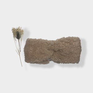 Könnte beinhalten: Ein braunes, flauschiges Stirnband mit einem gedrehten Design.