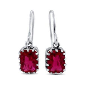 May include: A pair of silver dangle earrings with red gemstone accents. The earrings feature a rectangular shaped gemstone with a silver frame.