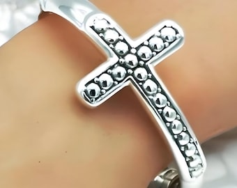 May include: Silver cross bracelet with a beaded design. The bracelet is open and has a hinged clasp.