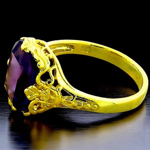 May include: A gold ring with a large, faceted, purple gemstone set in a filigree design. The ring is marked "SS" on the inside of the band.