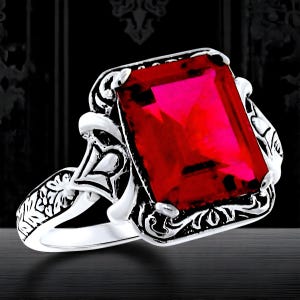 May include: A silver ring with an ornate design and a large, red, rectangular gemstone.