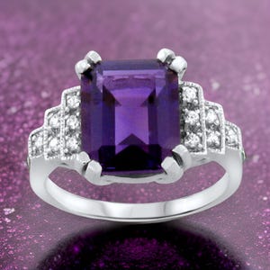 May include: A silver ring with a large, rectangular, purple amethyst gemstone surrounded by smaller, clear diamonds.