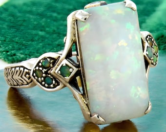 May include: A silver ring with a large rectangular white opal gemstone and smaller green gemstones set in the band.