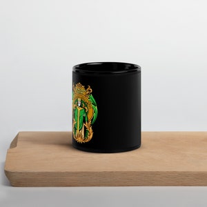 May include: Black ceramic mug with a gold and green design featuring a saint holding a staff. The design includes the text "Saint Patrick's Day" and "Erin Go Bragh".