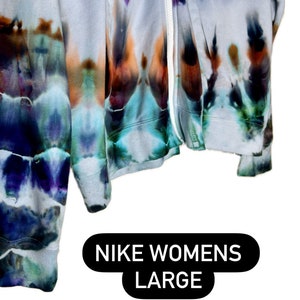 Pode incluir: Um moletom com z&iacute;per tie-dye em tons de azul, roxo e laranja. O moletom &eacute; etiquetado como "NIKE WOMENS LARGE".