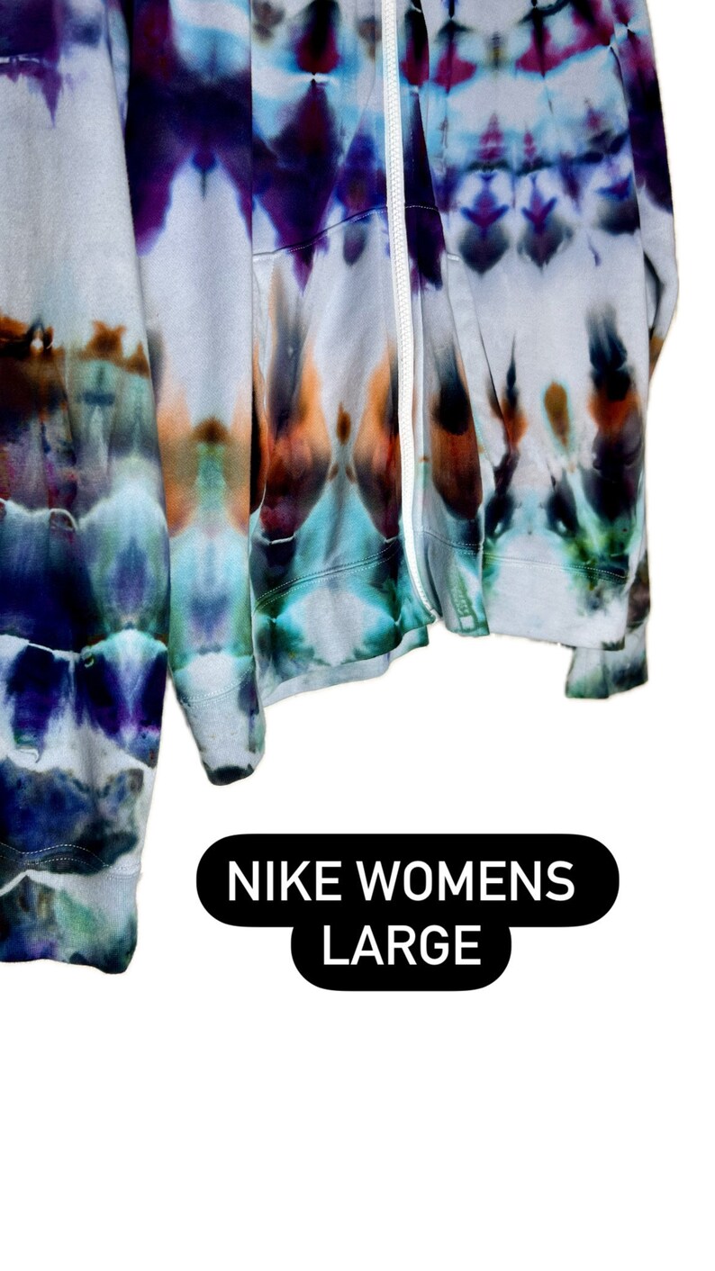 Pode incluir: Um moletom com z&iacute;per tie-dye em tons de azul, roxo e laranja. O moletom &eacute; etiquetado como "NIKE WOMENS LARGE".