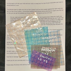May include: Four clear silicone inserts for resin crafts. The inserts are labeled "Gem", "Ambrosia 5x1", "Ambrosia 4x3", and "Confetti 3.5 x 2".