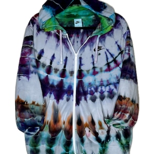 Pode incluir: Uma jaqueta com capuz de z&iacute;per tie-dye com fundo branco e um logotipo Nike swoosh preto. A jaqueta tem uma variedade de cores, incluindo roxo, azul, verde e laranja.