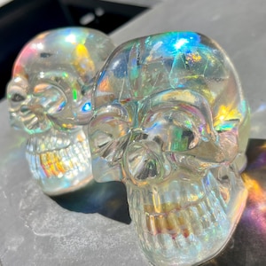 Peut inclure: Deux figurines de crâne en verre transparent iridescent. Les crânes sont détaillés et ont un reflet arc-en-ciel.