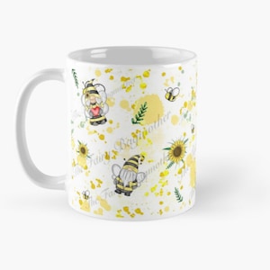 May include: White ceramic mug with a yellow and white pattern of gnomes wearing bee costumes, bees, sunflowers, and the text "The Fairy Big Brother The Fairy Big Mother".