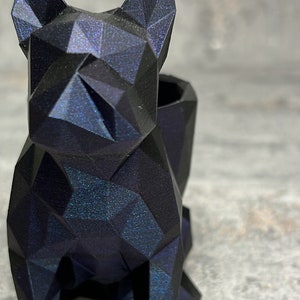 Könnte beinhalten: Ein geometrischer Bulldoggen-Blumentopf in Schwarz und Blau mit glitzernder Oberfläche. Der Topf ist aus 3D-gedrucktem Material gefertigt und hat eine strukturierte Oberfläche.