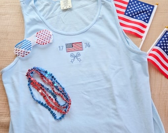 Camiseta sin mangas con la bandera estadounidense bordada de 1776, colores cómodos, teñida en prenda, con lazo moderno en rojo, blanco y azul.