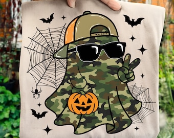 Op de afbeelding: Beige draagtas met een Halloween-geest met een zonnebril en een camouflagecape. De geest houdt een oranje pompoen vast en geeft een vredesteken. Het ontwerp bevat vleermuizen, spinnenwebben en sterren.