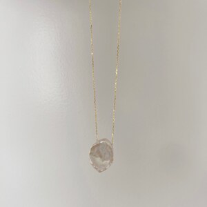 May include: A delicate gold chain necklace with a large, irregular-shaped, white pearl pendant.