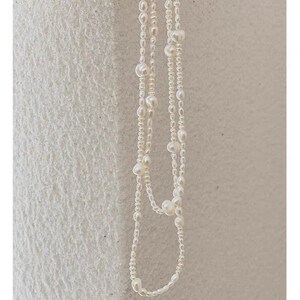 May include: A white pearl necklace with multiple strands of small pearls and larger pearls interspersed throughout.