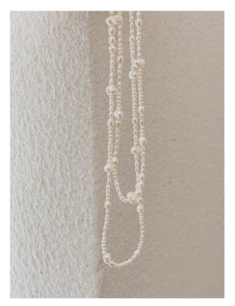 May include: A white pearl necklace with multiple strands of small pearls and larger pearls interspersed throughout.