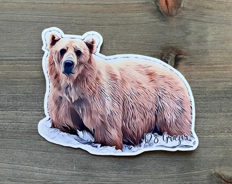 Puede incluir: Una pegatina de un oso marrón con un contorno blanco. El oso está mirando hacia adelante con la boca cerrada. La pegatina tiene el texto "128 Grazer" en la esquina inferior derecha.