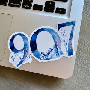 May include: A blue and white watercolor sticker with the number 907. The sticker features a mountain range and trees in the background.