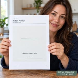 Peut inclure: Un planificateur budgétaire en papier blanc avec du texte noir indiquant Budget Planner, A little clarity for your money, Plan gently. Make it yours., et This planner belongs to. Le document présente un encadré gris clair avec des lignes.