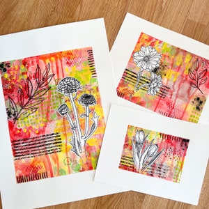 May include: Three art prints with red, yellow, and green backgrounds featuring black and white floral illustrations. The prints are mounted on white cardstock.
