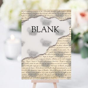 May include: A blank card with a torn paper design, featuring the word "BLANK" in bold black letters. The card is propped up on a small wooden easel, suitable for various occasions.