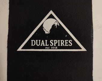 May include: Black and white patch with a triangle design. The triangle contains a stylized mountain range and a moon. The text "DUAL SPIRES est 1918" is printed below the mountain range.