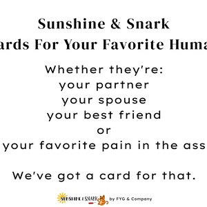 May include: A white sign with black text reading: Sunshine & Snark, Cards For Your Favorite Human, Whether they're: your partner, your spouse, your best friend, or your favorite pain in the ass, We've got a card for that. Includes a small logo at the bottom.