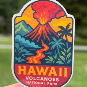 May include: A colorful sticker featuring a volcano erupting with red and orange lava and smoke against a yellow and orange sky. The sticker has the text "HAWAII VOLCANOES NATIONAL PARK" in red and white.