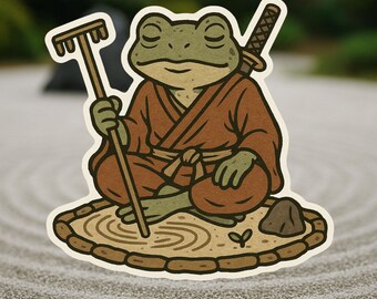 Pode incluir: Um autocolante com um sapo de desenho animado em um roupão marrom, sentado em pose meditativa em um jardim de areia. O sapo tem uma katana nas costas e segura um ancinho. O jardim de areia tem uma pedra e uma pequena planta.
