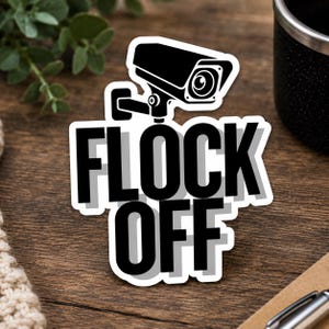 May include: A die-cut sticker featuring a black and white graphic of a security camera positioned above the bold, black, sans-serif text that reads FLOCK OFF. The design includes a subtle gray drop shadow behind the lettering on a white background.