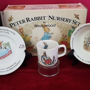 Peut inclure: Un ensemble de chambre d'enfant Peter Rabbit par Wedgwood, comprenant une assiette, un bol et une tasse avec des illustrations de Peter Rabbit. L'ensemble comprend une boîte avec le texte "Peter Rabbit Nursery Set".