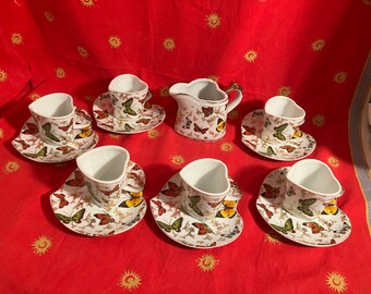 May include: A set of six heart-shaped teacups and saucers featuring a butterfly design. The cups and saucers are white with a colourful butterfly pattern. There is also a matching creamer.