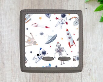 May include: A gray light switch cover with a white background featuring a repeating pattern of astronauts, robots, rockets, stars, and flying saucers. The pattern is in a watercolor style.