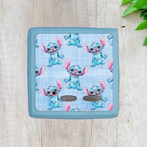 May include: A blue zippered pouch with a repeating pattern of Stitch, a blue alien character with pink ears and a mischievous grin, on a light blue background.