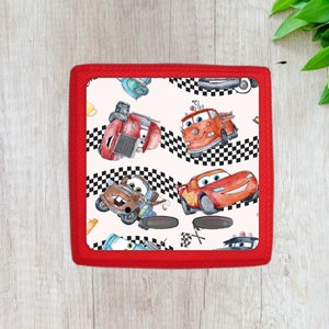 May include: Red, white, and black checkered race track pattern with cartoon images of red, orange, and brown cars. The background is white with a red border.