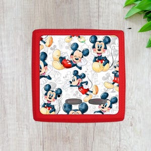 May include: Red square-shaped cushion with a white background and a repeating pattern of Mickey Mouse in various poses. The cushion has a red border.