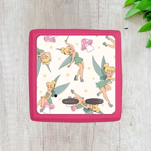 May include: Pink fabric case with a white background featuring a repeating pattern of Tinkerbell fairies with green wings and pink mushrooms.