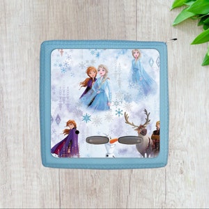 May include: A blue zippered pouch with a Frozen theme. The pouch features images of Elsa, Anna, Olaf, and Sven against a white background with snowflakes.